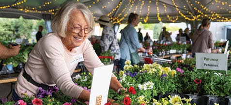 A woman is smiling while holding a sign with a potted plant. AI generated content