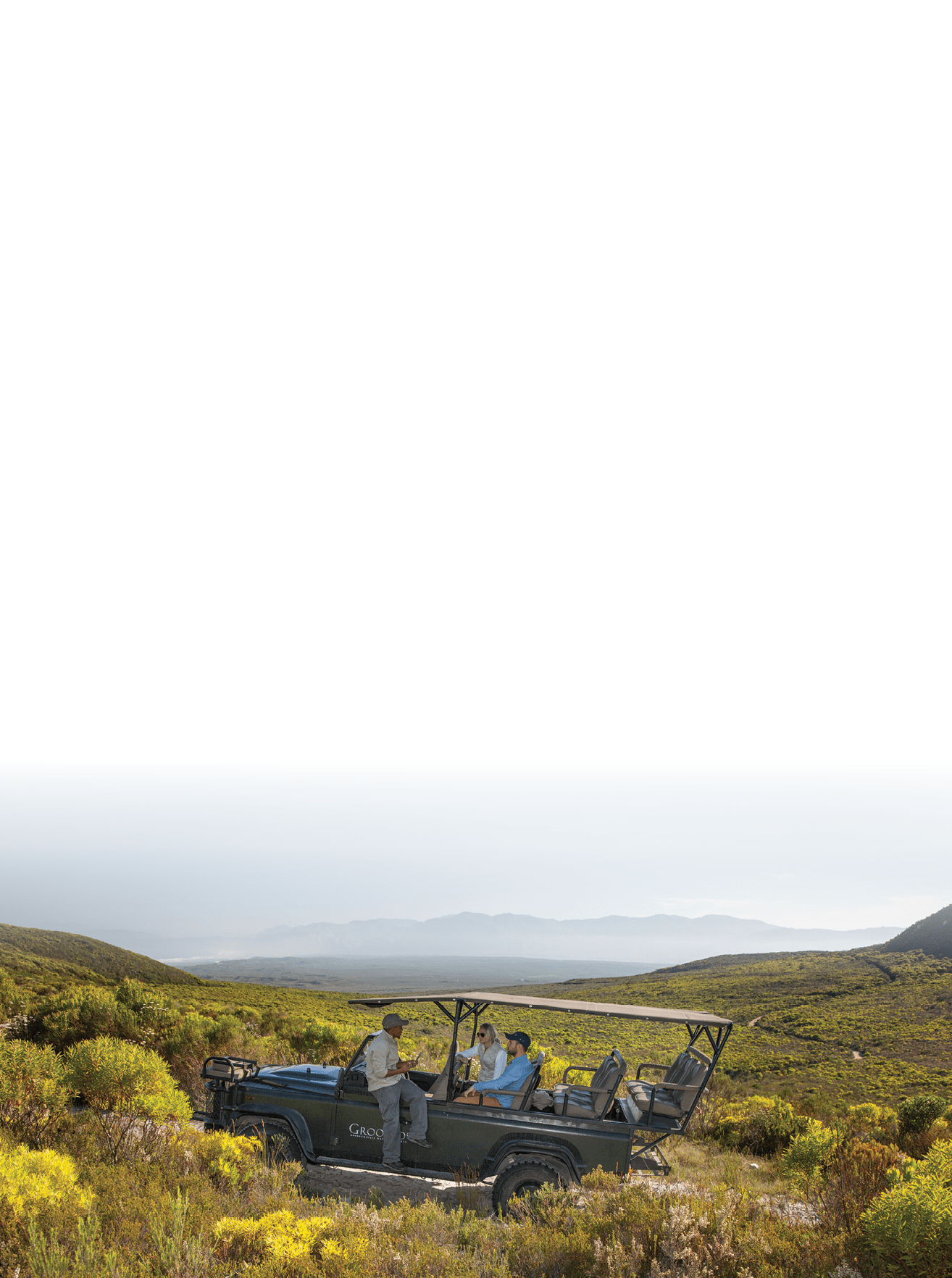 A group of people are riding in a jeep through a field with mountains in the background. AI generated content