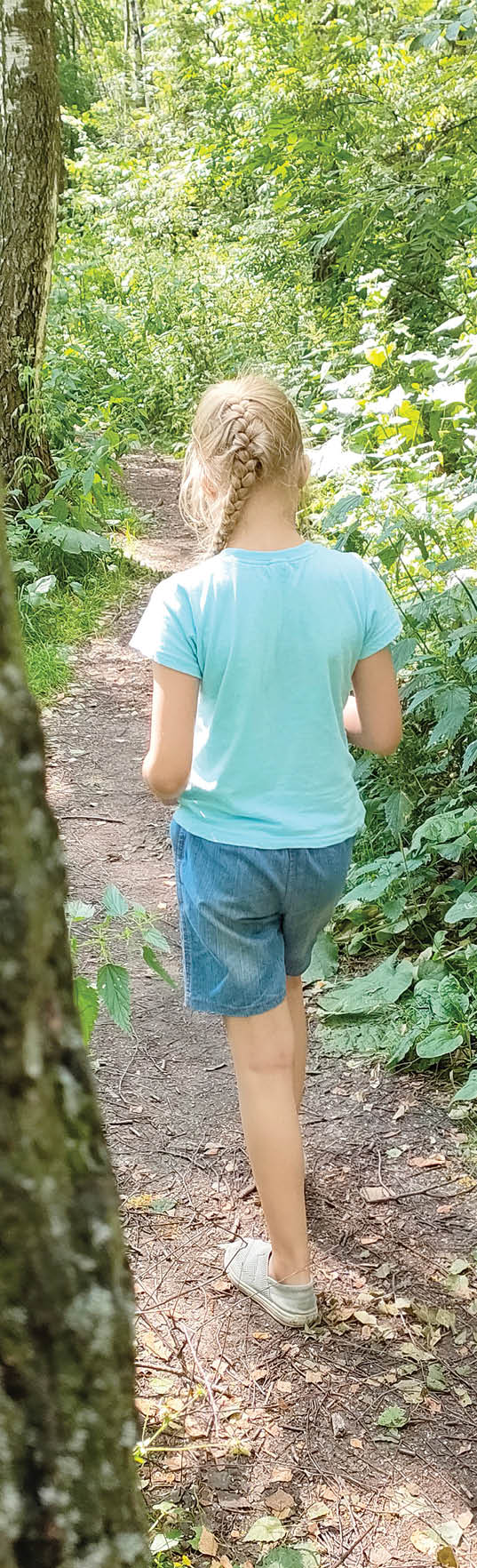 A woman is walking on a dirt trail in a wooded area. AI generated content