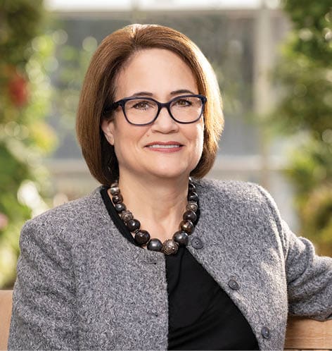 A woman wearing glasses and a suit is sitting on a bench. AI generated content