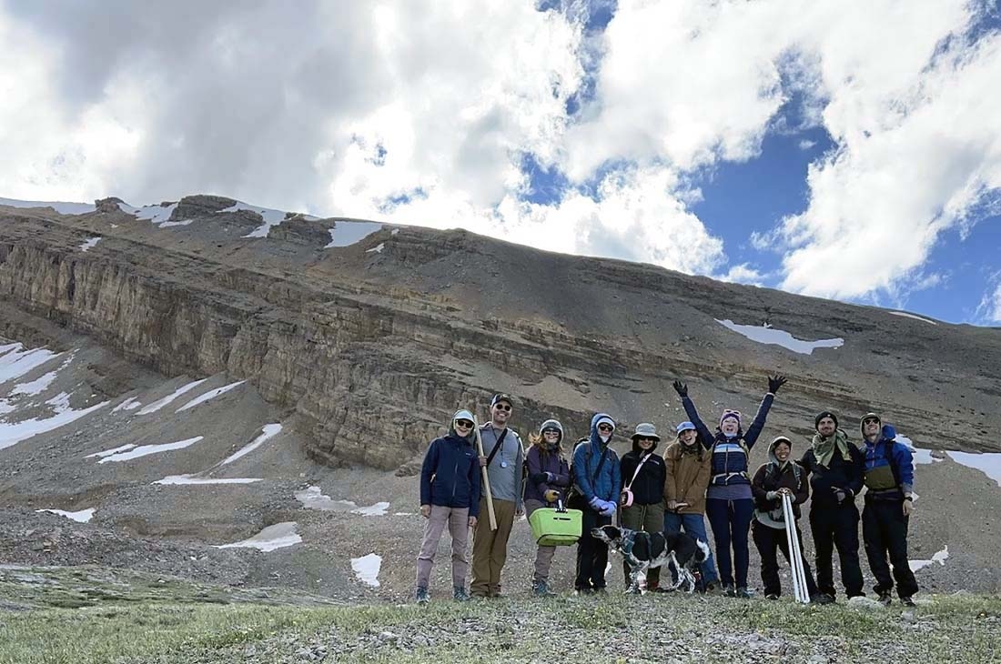 A group of scientists posing in front of a mountain