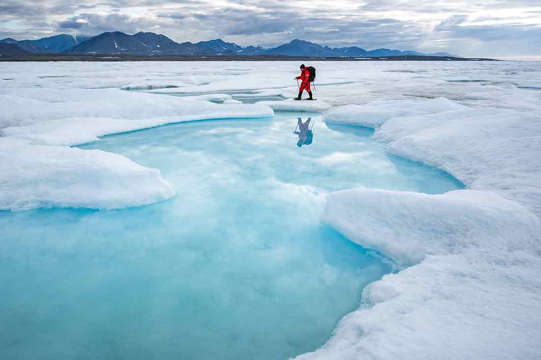Aka Simonsen, a native Greenlandic archaeologist, treks past an open melt pool on the sea ice between Inuit Qeqertaat (Kaffeklubben Island) and the mainland. An archaeologist treks past an open melt pool on the sea ice between Inuit Qeqertaat (Kaffeklubben Island) and the mainland.