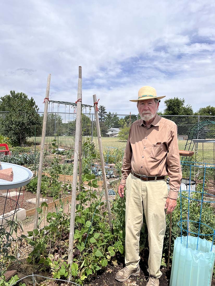 Older man in straw hat standing by garden plot
