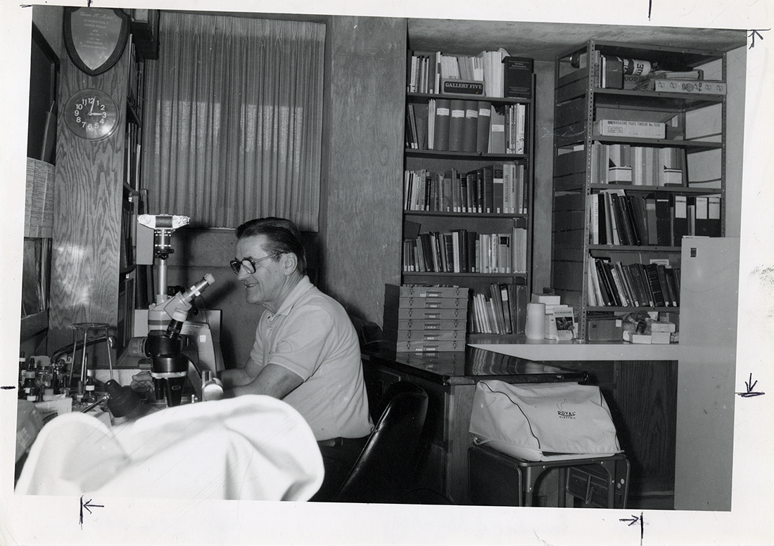 old photo of man looking through microscope
