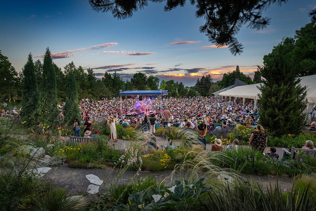 Concert in an amphitheater outside in a large garden, with people looking at the stage