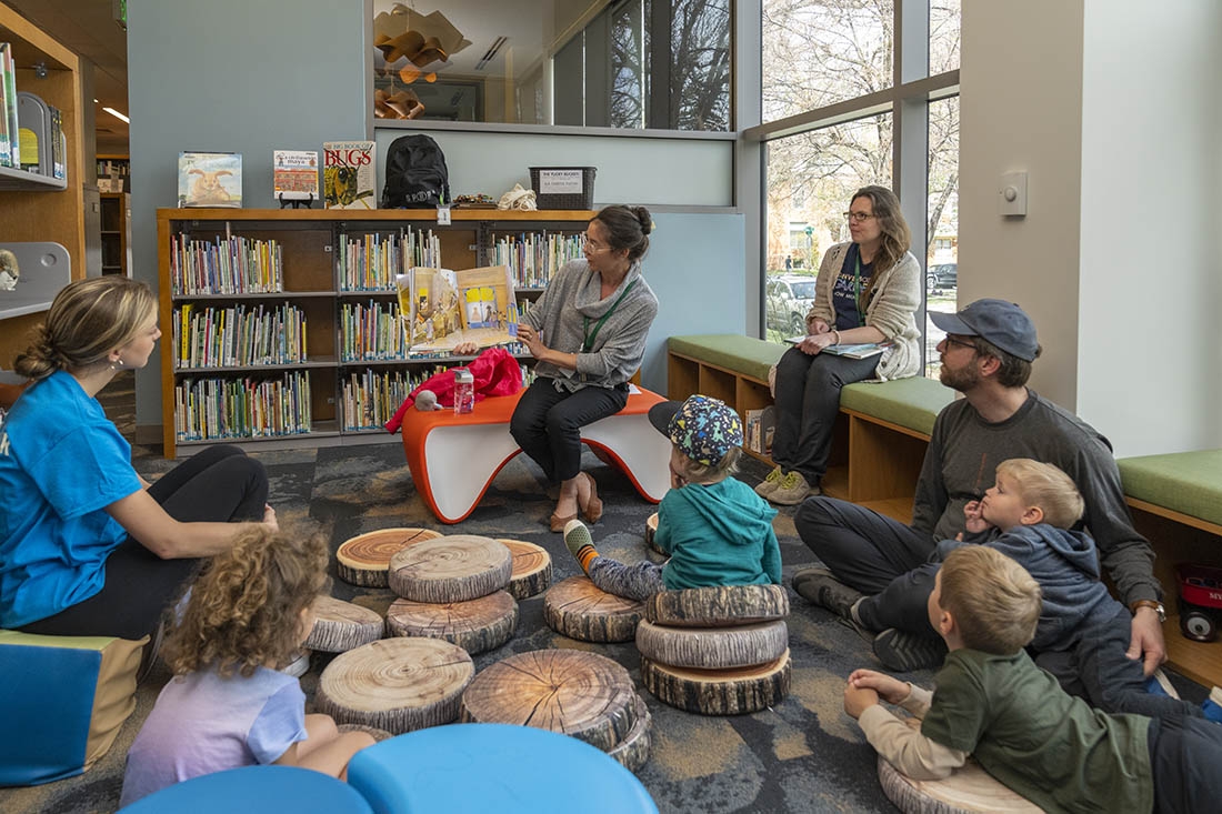 Woman reading from picture book to group of children and adults