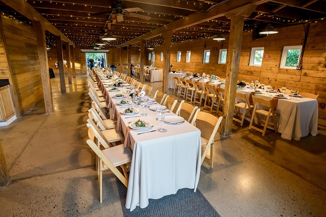Long tables with chairs are set during a wedding reception.