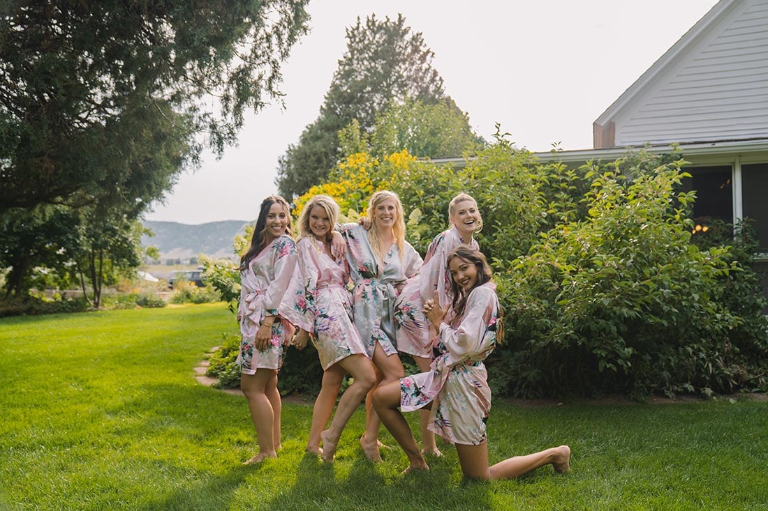 Smiling bride and bridesmaids outside wearing their robes, getting ready to put on their dresses