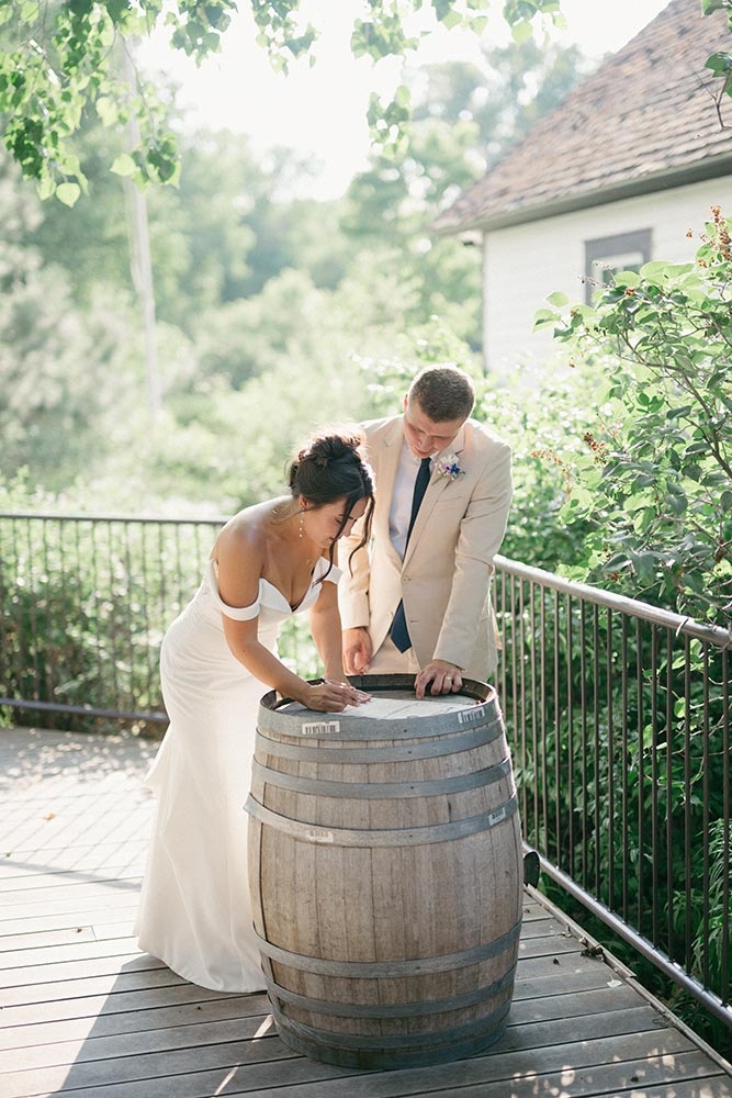 Bride and groom outside signing wedding certificate that is sitting on a barrel
