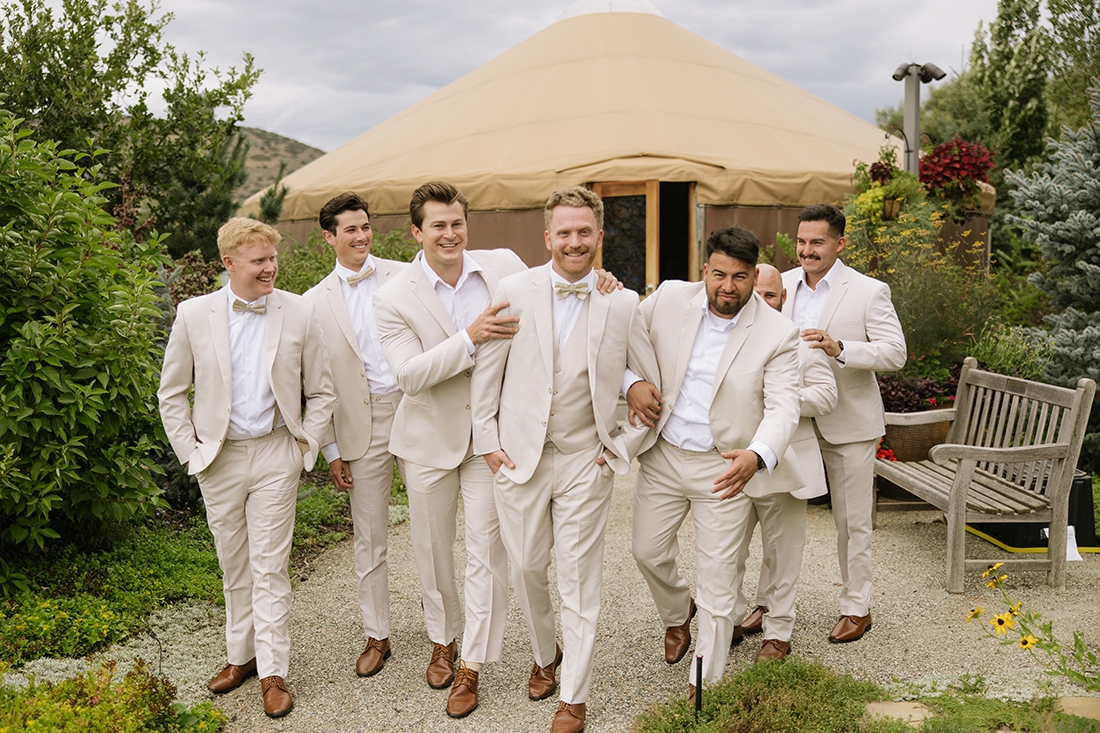 Smiling groom and groomsmen outside of a yurt getting ready to go to the wedding.