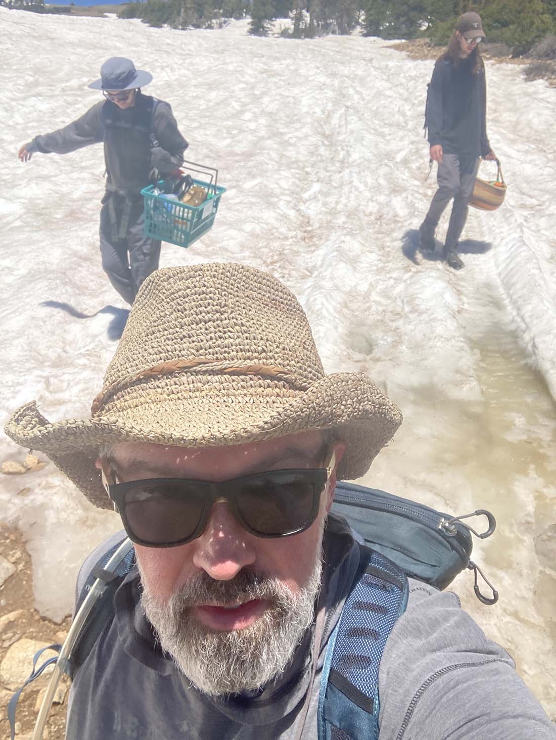 Three men on snowfield with one in foreground taking selfie