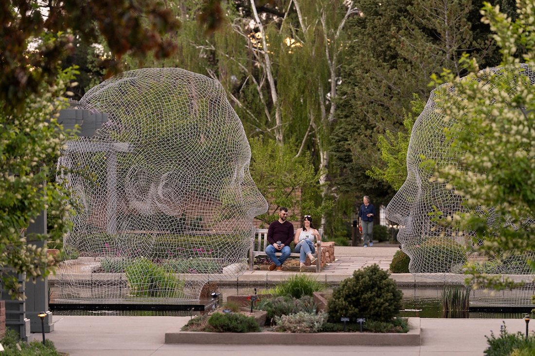Two Jaume Plensa sculptures in a pool in a garden