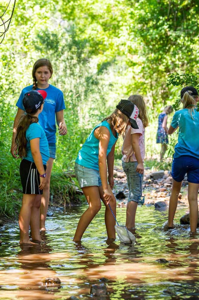 Chatfield Farms Adult and children pointing at water in a river at Chatfield Farms
