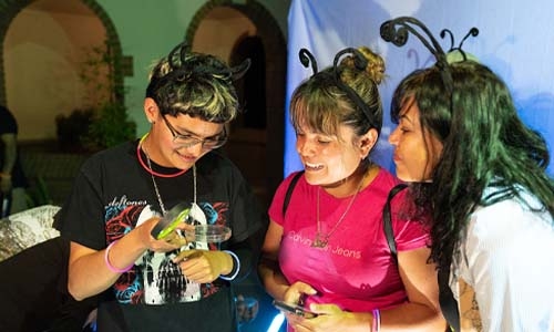 Three young people observing an insect