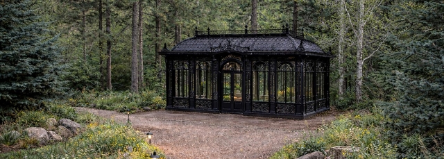 Black solarium outside, surrounded by trees.