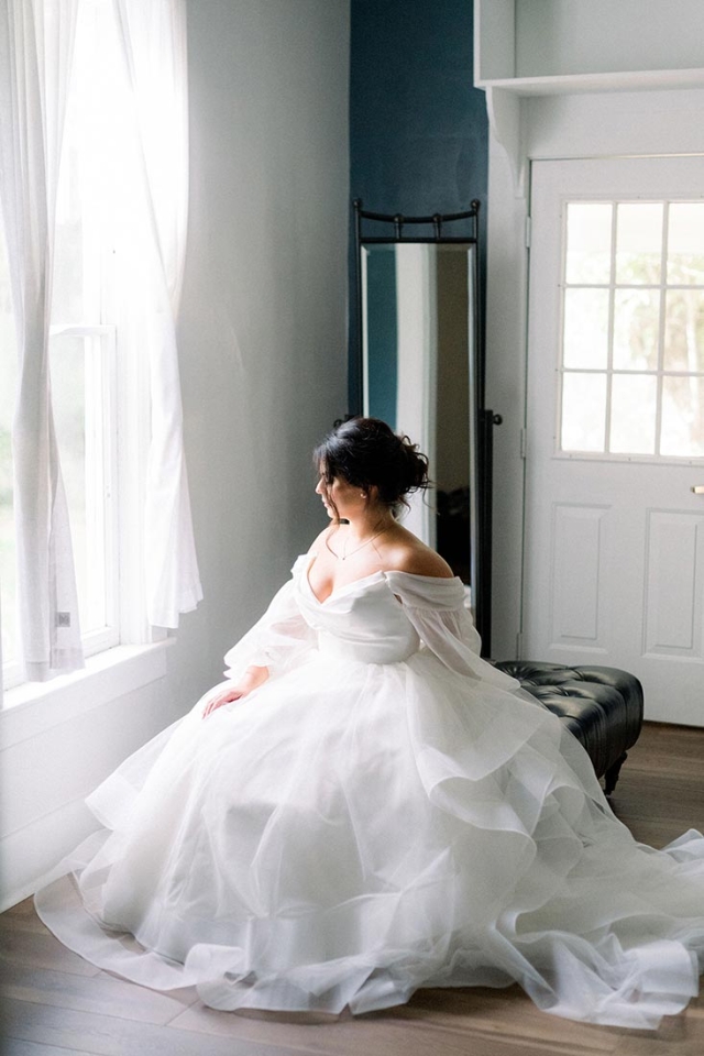 Seated bride looking out of a sunny window