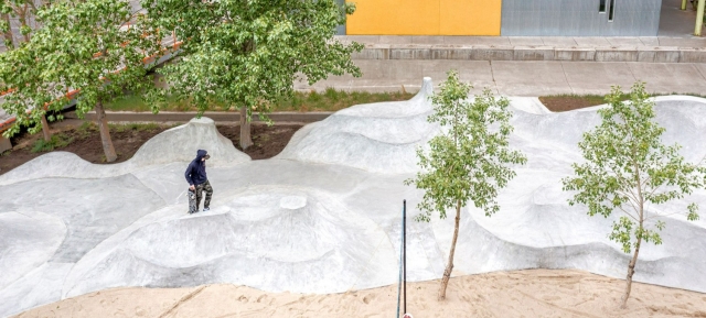 Person walking on a snow-like hill with two trees in the foreground