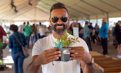 man holding up some plants and smiling