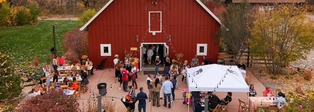 Red barn in the background with people mingling outside in the foreground