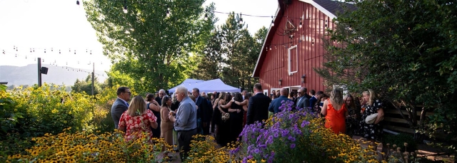 Red barn at dusk with a group of people outside of the barn during a party.