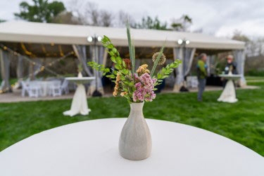 Table with a vase of flowers in the foreground, a tent is in the background