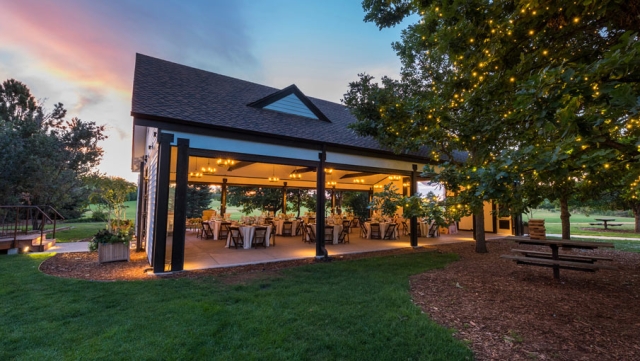 Stable with the sides open at sundown. Tables and chairs are in the stable 