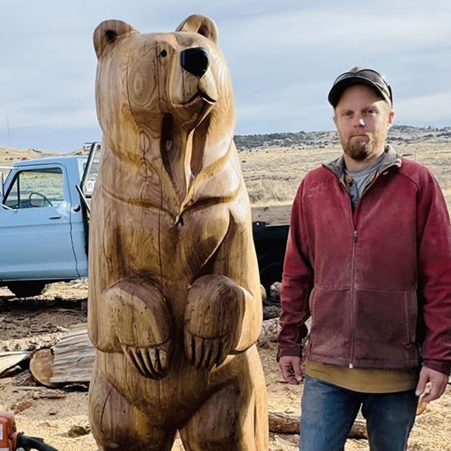Kenny Rathbun standi g next to a life-sized carved bear